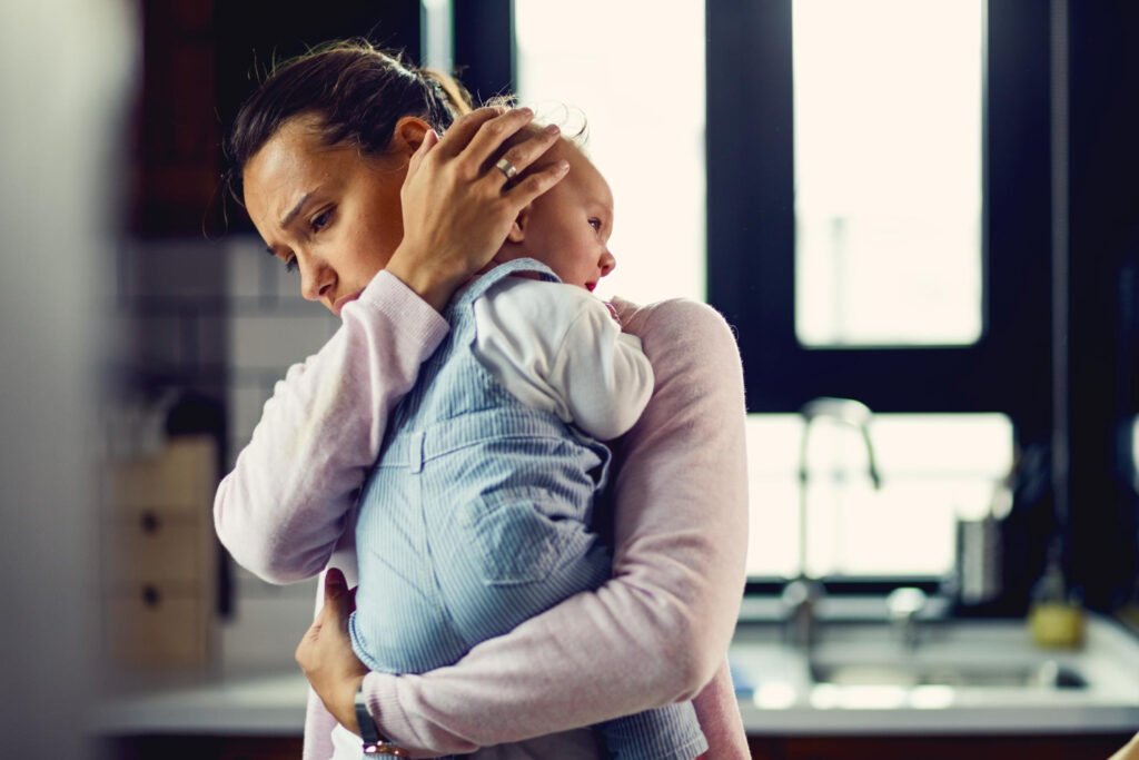 Parent comforting an overtired baby showing signs of tiredness and sleep deprivation
