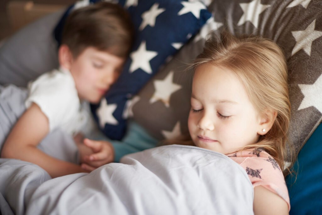 Young child sleeping peacefully in bed during an afternoon nap, supporting healthy sleep and development.