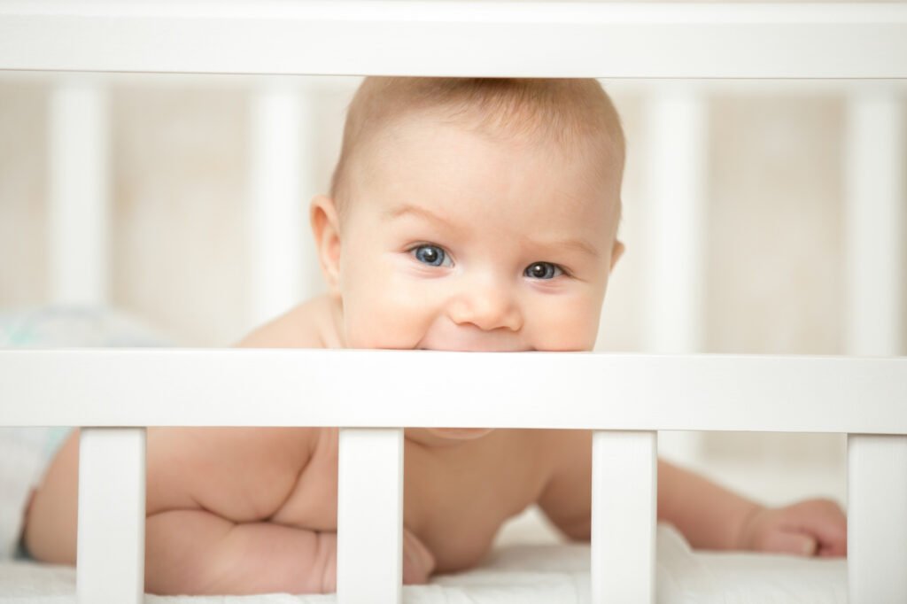 Happy baby awake in a cot, white noise for babies.